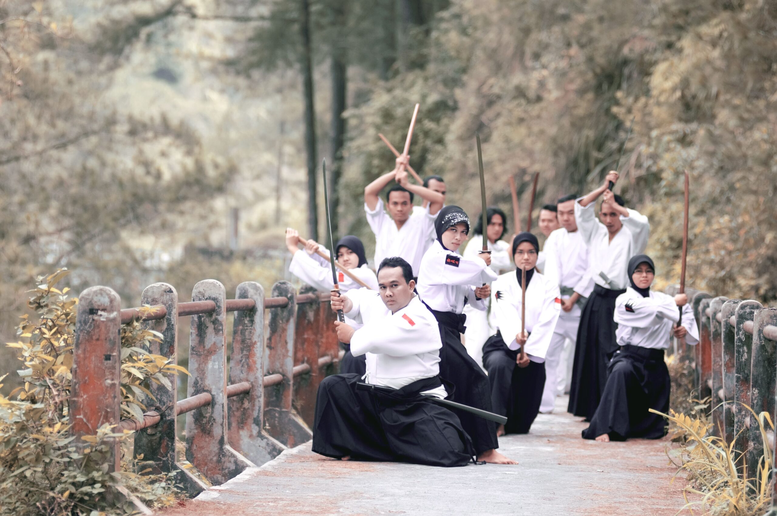 A group practicing martial arts with swords on a bridge in Jogja, Indonesia.